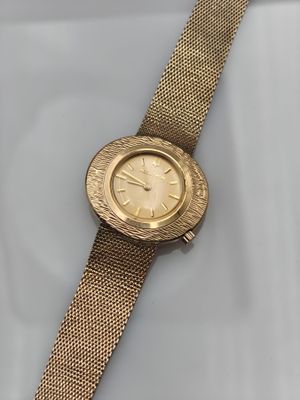 gros plan d'une montre-bracelet en or sur une surface blanche