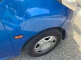 a small blue car parked on the side of the street