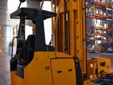 a forklift in a large warehouse with pallets in the background