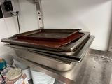 several pans of food are stacked on a metal shelf in a kitchen