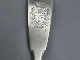 a silver spoon with a crest on it sitting on top of a table