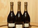 trois bouteilles de vin posées sur un tonneau en bois