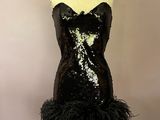un mannequin orné de plumes noires, posé sur un socle
