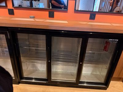 un homme debout devant une vitrine à trois portes en verre