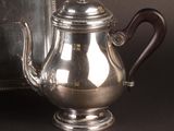 a silver tea pot sitting next to a silver vase