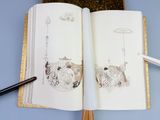 an open book with a drawing on it next to a pen