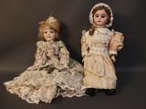 pair of antique dolls sitting next to each other on a black background