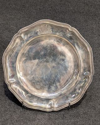 un plat en argent ancien posé sur une table, sur fond noir