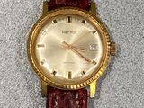 a gold wrist watch on a red leather strap