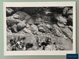 a black and white photo of a group of people sitting on a rock
