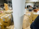 a man standing next to a tall white object in a warehouse