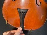 an old violin being held up by a person ' s hand