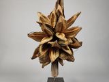 sculpture représentant une fleur sur un socle en bois, sur fond blanc