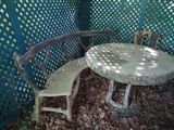 two chairs and a table in the shade of a tree