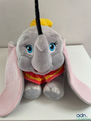 stuffed elephant sitting on a white table with a yellow hat on top of it