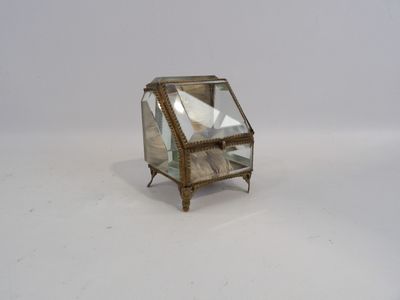 une image représentant une petite boîte en verre posée sur une surface blanche