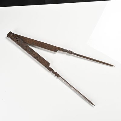 une paire de vieux outils en métal posés sur une surface blanche, sur fond noir