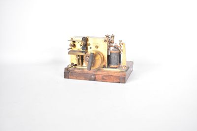 une petite maquette de machine à vapeur posée sur un socle en bois