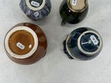 four different colored vases sitting on top of a white surface