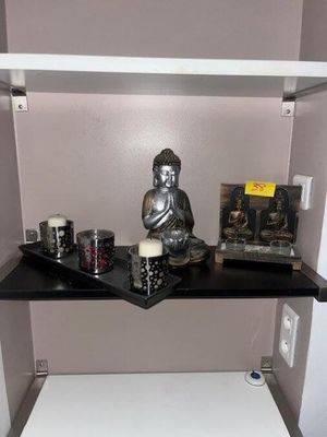 une petite étagère sur laquelle trône une statue de Bouddha