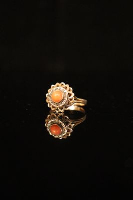 an image of a gold ring with coral stones on a black surface