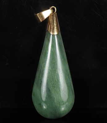 un gros plan d'un pendentif en jade vert en forme de larme sur fond noir