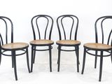 quatre chaises noires avec des assises en osier, sur fond blanc
