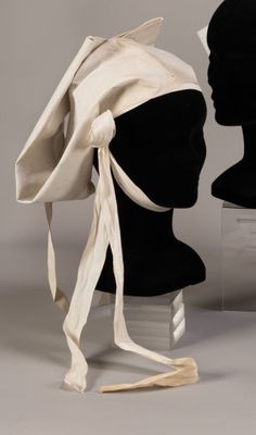 two mannequin heads and a hat on display on a table