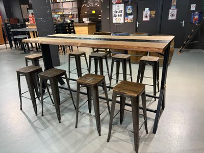 Des tables et des tabourets sont disposés dans une pièce aux murs noirs.