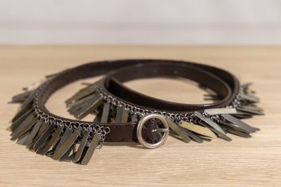 two leather bracelets with metal fringes on a wooden surface