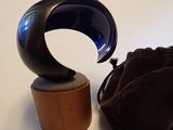un objet en verre bleu posé sur un socle en bois, à côté d'un sac noir