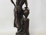 bronze statue of a woman with a vase on a pedestal