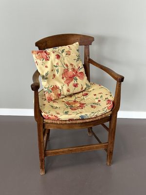 une chaise en bois avec un coussin posé dessus, dans une pièce