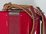 a red suitcase with a brown strap on top of it