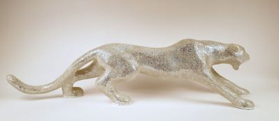 a silver figurine of a cheetah running on a white surface