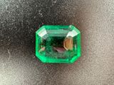 a close up of a green emerald stone on a silver surface