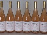 six bottles of pink wine are lined up on a table