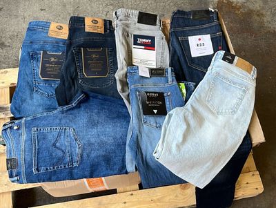 Plusieurs paires de jeans pour hommes sont empilées sur une palette
