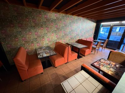 des tables et des chaises dans une pièce, avec un mur tapissé derrière elles
