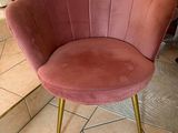 a pink chair with gold legs on a tile floor