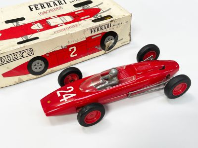 une petite voiture de course rouge à côté d'une boîte encore emballée
