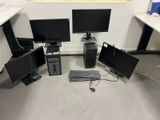 trois écrans d'ordinateur et un clavier posés par terre