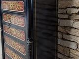 an image of a black and gold chest of drawers against a brick wall
