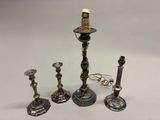 trois bougeoirs en argent et un porte-bougie sur fond blanc