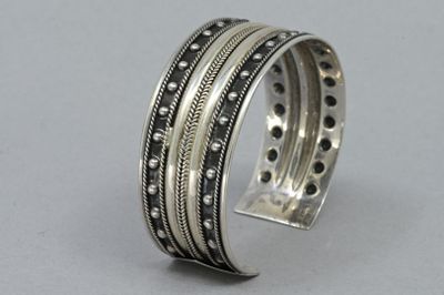 un gros plan d'un bracelet en argent parsemé de petits points noirs