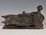 une statue antique en bronze représentant une femme allongée avec un chien