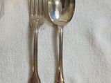 deux cuillères en argent et une fourchette posées sur une nappe blanche
