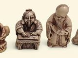 three figurines of people sitting on a table with a white background