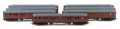 three red train cars are lined up on a white surface