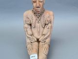 statue représentant un homme assis par terre, les mains posées sur les genoux